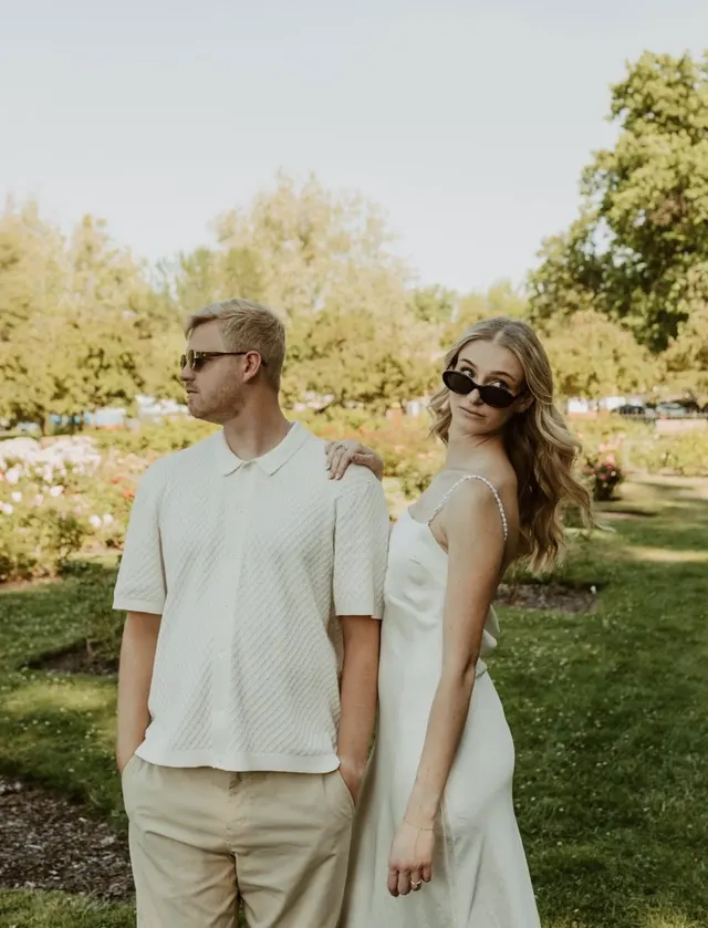 A couple in sunglasses posing in a garden