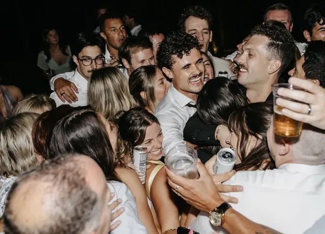 Friends packed together on the dance floor, drinks in hand