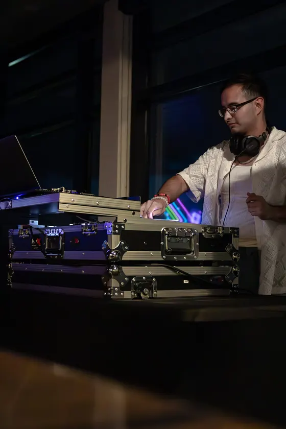 DJ Manny mid-set in a booth washed in blue light