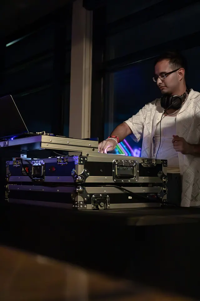 DJ Manny mid-set in a booth washed in blue light