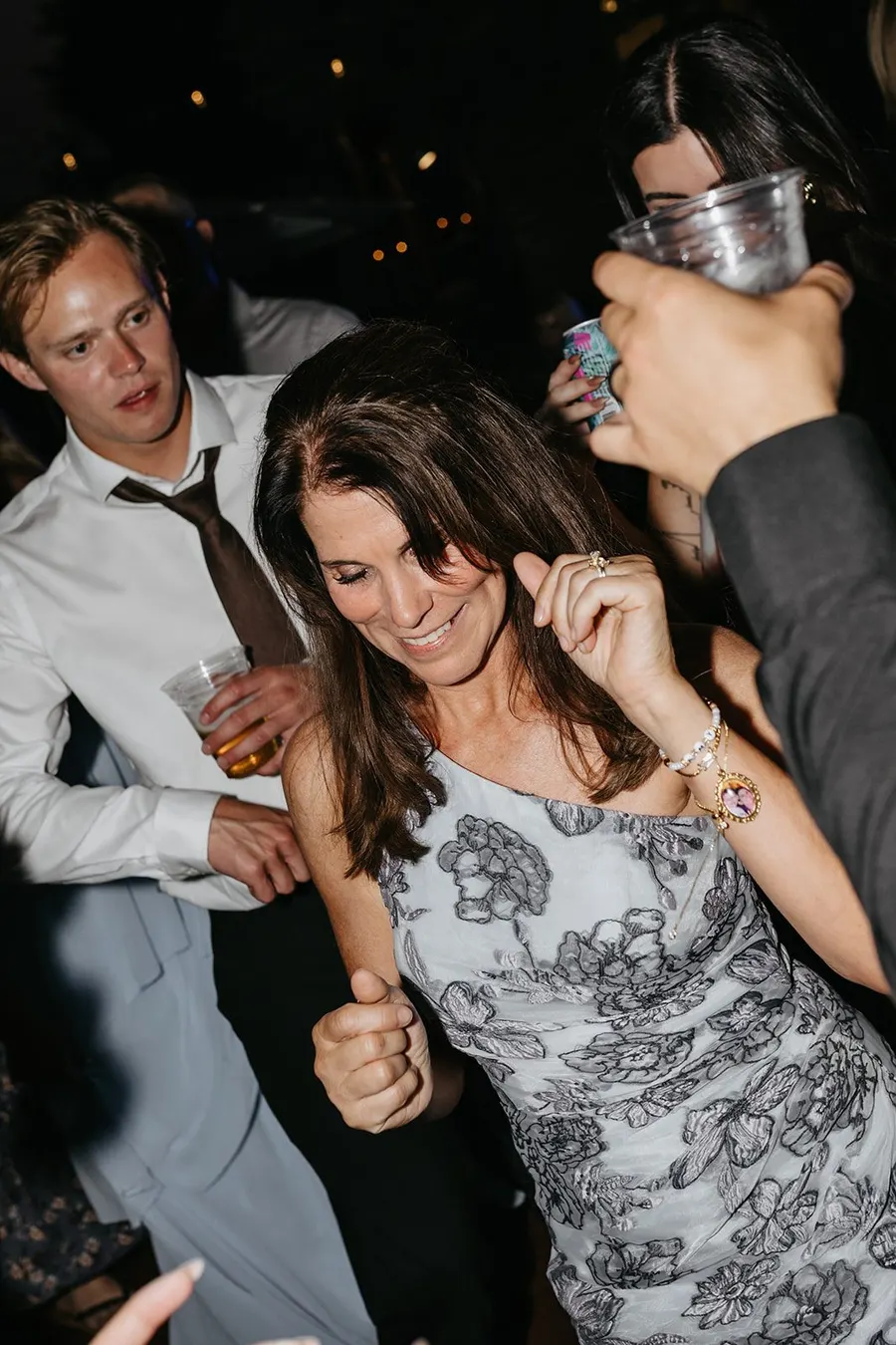 A packed wedding dance floor at night, guests crowded shoulder to shoulder and dancing under the lights