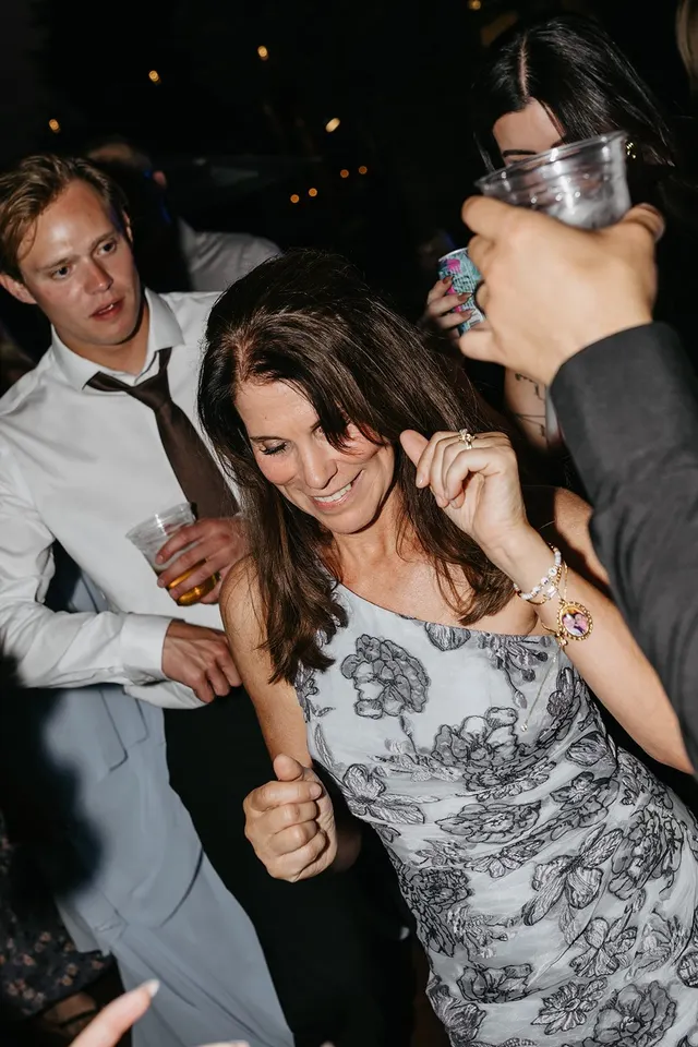 A packed wedding dance floor at night, guests crowded shoulder to shoulder and dancing under the lights
