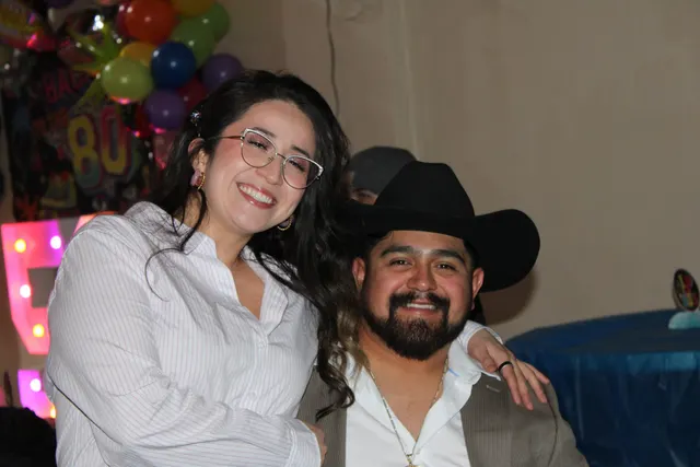 A couple smiling at a birthday celebration with balloons and marquee letters